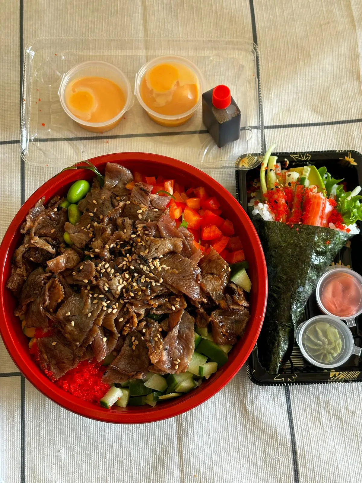 Rode poke bowl met rundvlees en sesam naast een temaki-handrol met surimi
