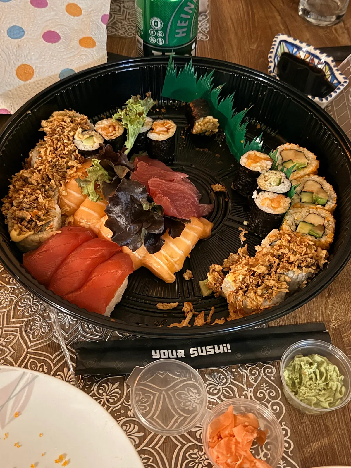 Ronde zwarte schaal met nigiri van zalm en tonijn, sashimi en rolls met krokante uitjes